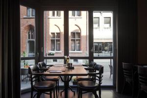 a table and chairs in a room with a large window at Hotel INGREDI in Bree