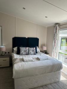 une chambre avec un grand lit avec une tête de lit bleue dans l'établissement Oakmont 4 - Lodge with Hot Tub, à Allerthorpe