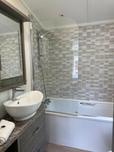 une salle de bain avec un lavabo et une baignoire et un lavabo dans l'établissement Oakmont 4 - Lodge with Hot Tub, à Allerthorpe