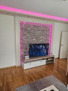 a living room with a tv and a brick wall at Apartmani Venera in Belgrade