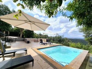 a swimming pool with an umbrella and a table and chairs at Lovely family home in the bush in Warmbaths