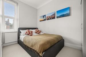 a bedroom with a bed with three pictures on the wall at Brand NEW 2 BR Fulham Apartment Near Tube Station COZY in London