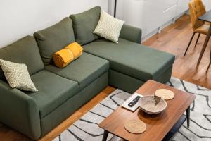a green couch in a living room with a table at Brand NEW 2 BR Fulham Apartment Near Tube Station COZY in London