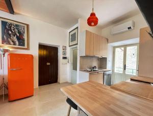 eine Küche mit einem orangefarbenen Kühlschrank und einem Holztisch in der Unterkunft Amiata Escape in Arcidosso
