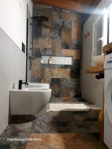 Un baño con inodoro blanco y pared de piedra. en Agrivilla Holiday Vacation Home, en Padresergio 27 fotos más