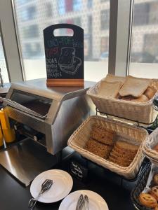 a counter with baskets of bread and a box of bread at ibis Bucharest Politehnica in Bucharest