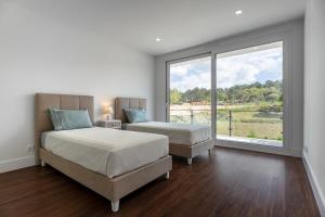 Dos camas en una habitación con una gran ventana. en Villa Serenity - Between golf and the sea, en Foz do Arelho 21 fotos más