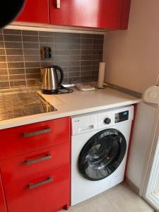 a washing machine in a kitchen with red cabinets at Anastasia's cozy studio in Nea Plagia +19 photos