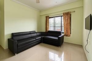 a living room with a black couch and a window at Stay Near Carithas & Matha Blue Bells by Haritha homes in Kottayam