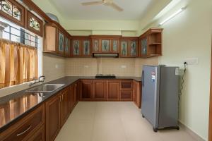 a kitchen with wooden cabinets and a stainless steel refrigerator at Stay Near Carithas & Matha Blue Bells by Haritha homes in Kottayam
