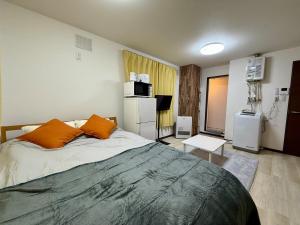 a bedroom with a large bed with orange pillows at 札幌中島公園徒歩圏内の宿泊施設室内はとてもおしゃれで綺麗な室内空間 in Sapporo