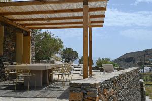 a patio with a table and chairs and a stone wall at Terramare Villa's 4 in Kithnos