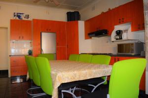 a kitchen with a table with green chairs and orange cabinets at Yaseens B&B in Ladysmith