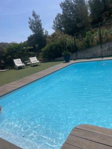 een groot blauw zwembad met twee stoelen in een tuin bij En Plein cœur des calanques à 800 m de la mer in Le Rove +8 foto's