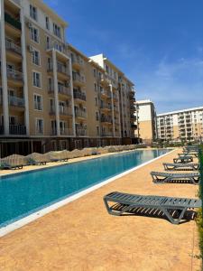 a swimming pool with lounge chairs in front of a building at Serenity Pool&Terrace Studio by Cosmopolis in Ştefăneştii de Sus