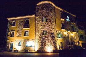 a large stone building with lights on it at night at Hotel Villa Torre Antica in Atena Lucana