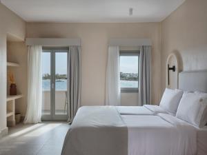 a white bedroom with a large bed and windows at Salt Suites Paros in Naousa +162 photos