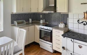 a kitchen with white cabinets and a stove top oven at 2 Bedroom Cozy Home In Melösa På Öland in Ekby