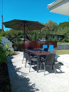 a wooden table with chairs and an umbrella at Sunday Villa in Agios Georgios