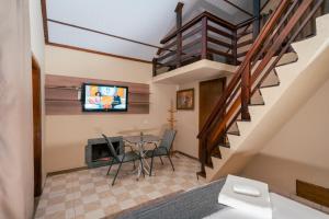 a living room with a dining room table and a staircase at Pousada Chalés Villa Pinhal in Santo Antônio do Pinhal