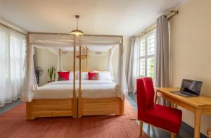 a bedroom with a canopy bed and a red chair at Summit Retreat in Moshi