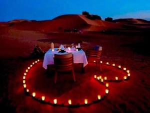 a table with chairs and lights in the desert at Merzouga heart camp in Merzouga