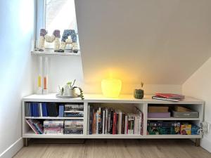 a white book shelf with books and a yellow vase at #LaMaisonVerte-calme en zone piétonne de Mulhouse in Mulhouse