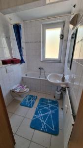 a bathroom with a tub and a sink and blue rugs at Fewo Linda - Gemütliche Ferienwohnung in direkter Bodenseenähe in Kressbronn am Bodensee