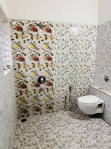 a bathroom with a toilet and a wall with flowers at Gulmohar Villa in Indore