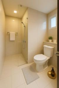 a bathroom with a toilet and a glass shower at Cozy 1BR near Solaire, Okada, Mall of Asia in Manila