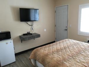 1 dormitorio con 1 cama y TV en la pared en Ace Budget Motel, en San Diego