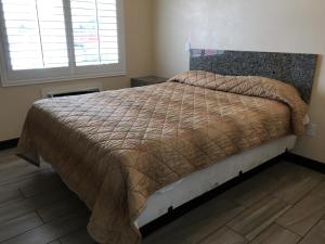 1 dormitorio con 1 cama grande y edredón marrón en Ace Budget Motel, en San Diego