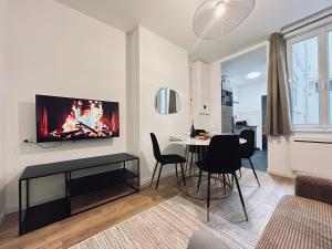 un salon avec une table et une télévision au mur dans l'établissement 1 Clairmarais T2 cosy a 2 pas du centre-ville, à Reims