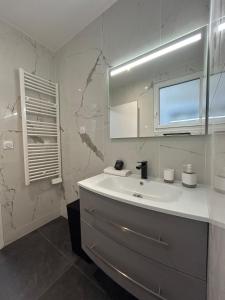 une salle de bain blanche avec un lavabo et une fenêtre dans l'établissement 1 Clairmarais T2 cosy a 2 pas du centre-ville, à Reims 18 autres photos
