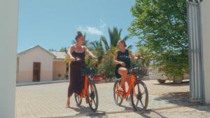 due donne in abiti eleganti che vanno in bicicletta su una strada di Coral Cliff Villas Zanzibar a Makunduchi