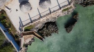 una vista aerea di una spiaggia e di un ponte sull'acqua di Coral Cliff Villas Zanzibar a Makunduchi