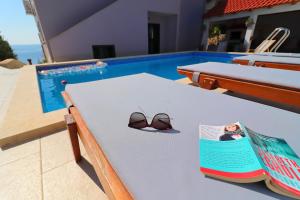 a pair of sunglasses sitting on a table next to a swimming pool at Villa Lavanda Korčula in Zavalatica +51 photos
