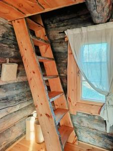 a ladder in a log cabin with a window at Nivan Majoitus in Joensuu