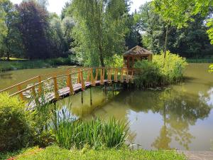 a wooden bridge over a pond with a gazebo at Namelis Eglių pasaka in Stripiniai