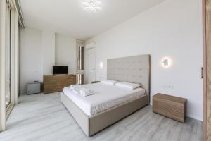 a white bedroom with a large bed and a television at The Ionian Villa Green Coast in Himare
