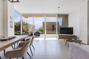 a living room with a table and chairs and a television at The Ionian Villa Green Coast in Himare