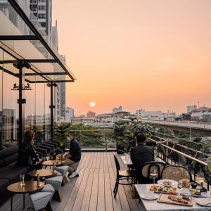 a group of people sitting at tables on a rooftop restaurant at Cascade Hotel Bangkok in Bangkok
