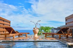 a patio with two benches and the ocean in the background at Villa Zarlor - 6 voyageurs in Petite Île