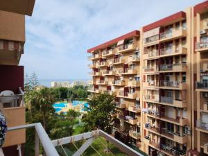 een hoog appartementengebouw met een zwembad op de achtergrond bij Benalmadena Minerva Apartamento con gran piscina in Benalmádena