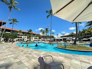 a pool at a resort with people swimming in it at Muro Alto Marulhos flat cinematográfico in Porto De Galinhas