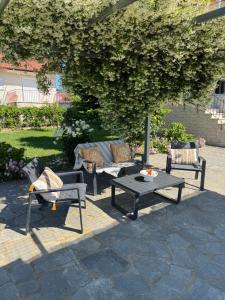 a patio with three chairs and a table and a couch at Country House Nannos in Néa Thésis