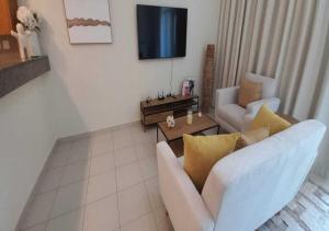 a living room with a white couch and a tv at Bay Square studio Bay view in Dubai