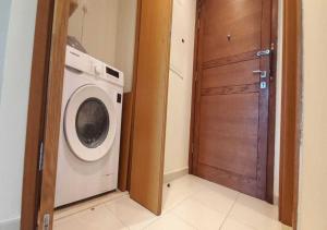 a laundry room with a washing machine and a wooden door at Bay Square studio Bay view in Dubai