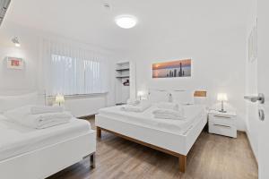 ルストにあるApartments Münchbach - near Europa-Park and Rulanticaの白い壁とウッドフロアのベッドルーム1室(ベッド2台付)