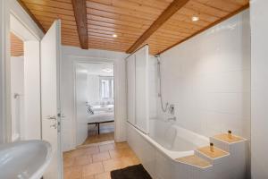 un bagno bianco con vasca e lavandino di M B Homes Schlatt Fewo 1 a Hechingen